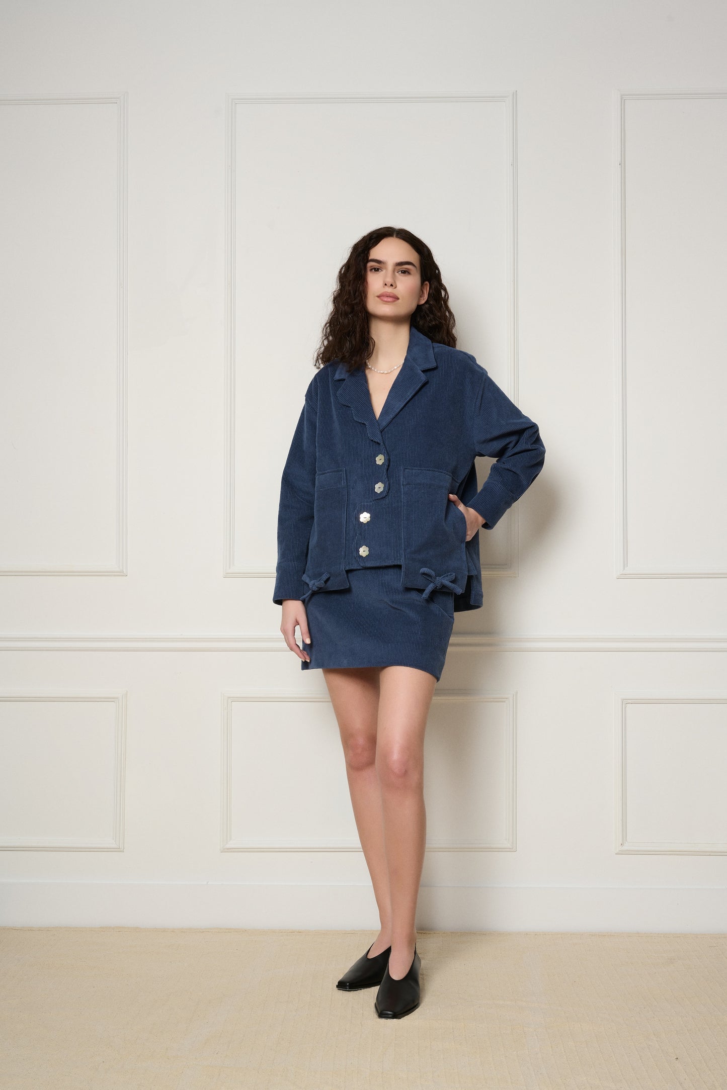 Woman wearing a blue matching set against a white paneled wall