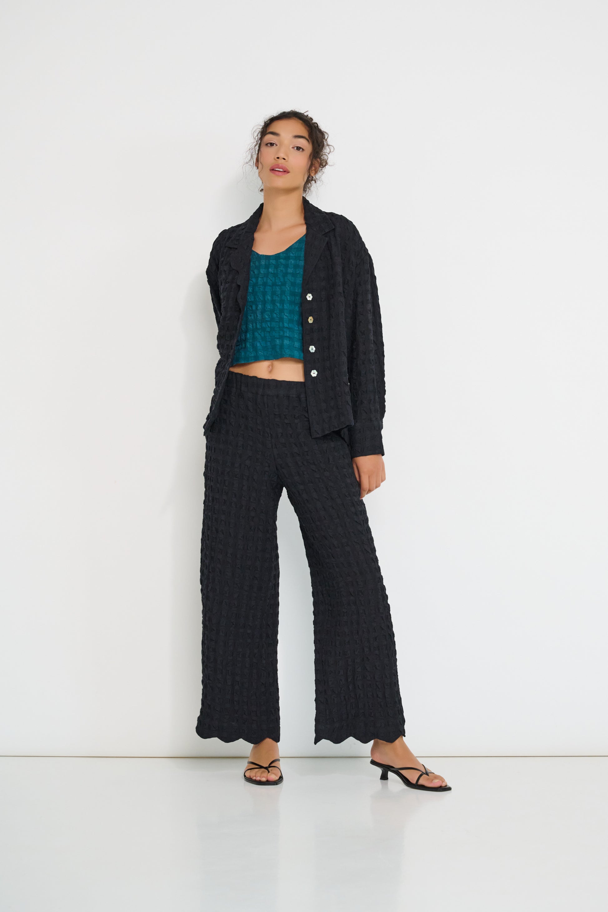 Voyage Pants black linen-viscose seersucker straight-leg pants with scalloped hem styled with Voyage Jacket matching set, made in Canada.