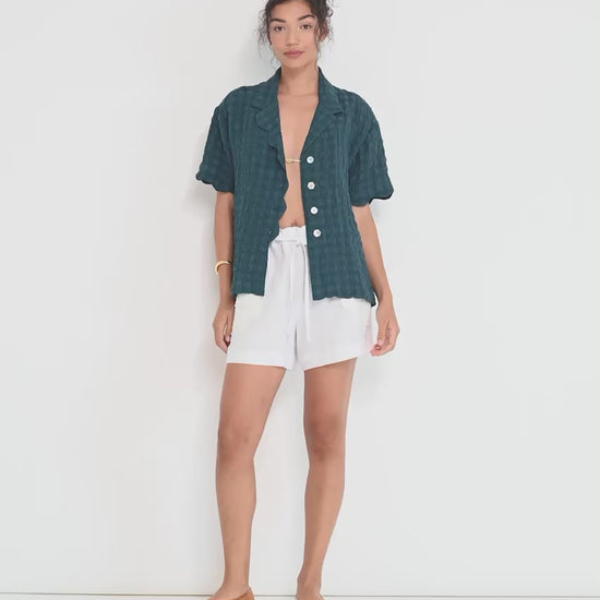 Stellaire Shorts in white linen with ivory lace patch pockets shown in movement, lightweight summer shorts made in Montreal