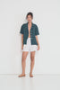 Stellaire Shorts in white linen with ivory lace patch pockets shown in movement, lightweight summer shorts made in Montreal